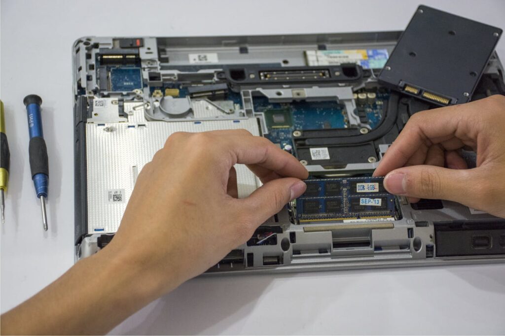 Close-up of a technician assembling a laptops internal components using tools.