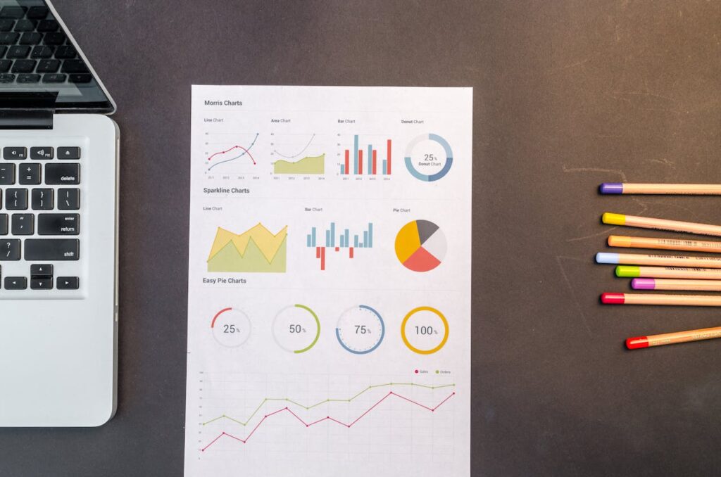 Top view of charts and colored pencils on a desk next to a laptop, perfect for business or education themes.